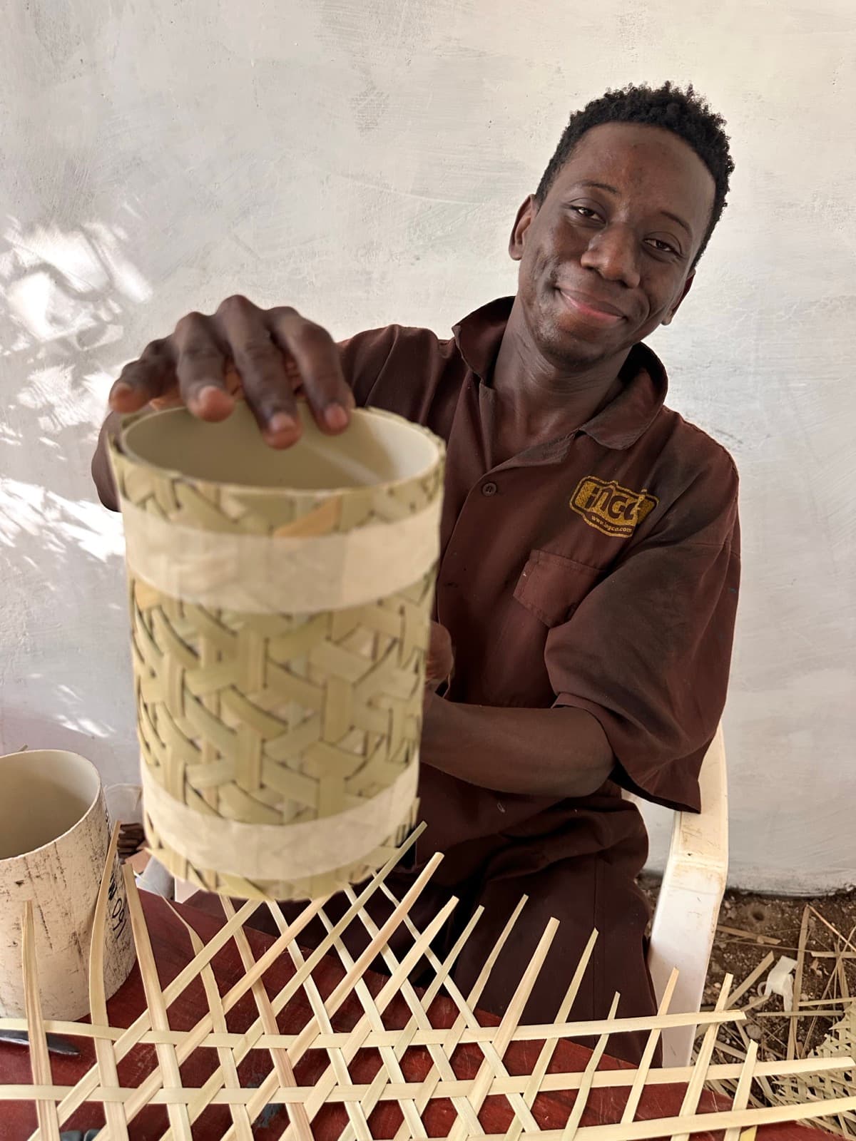 Craftsman smiling while holding the woven lantern body in his workshop