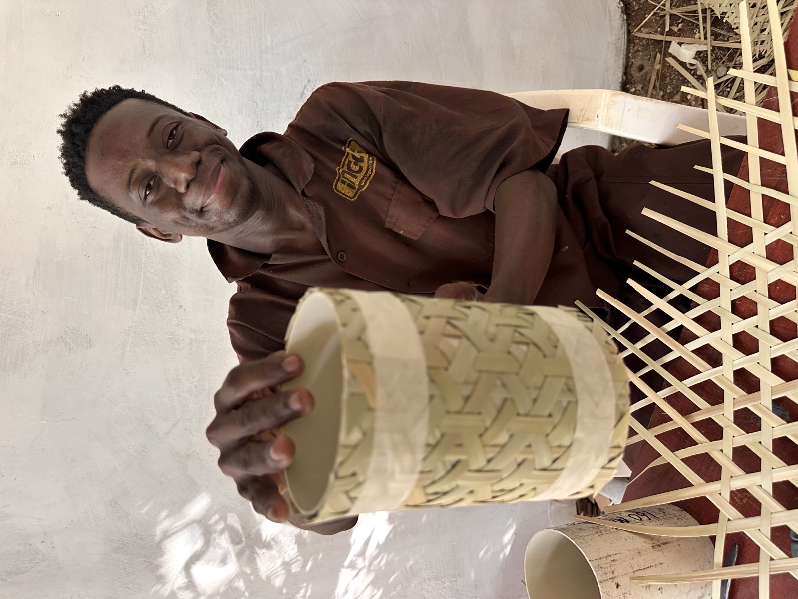 Craftsman smiling while holding the woven lantern body in his workshop